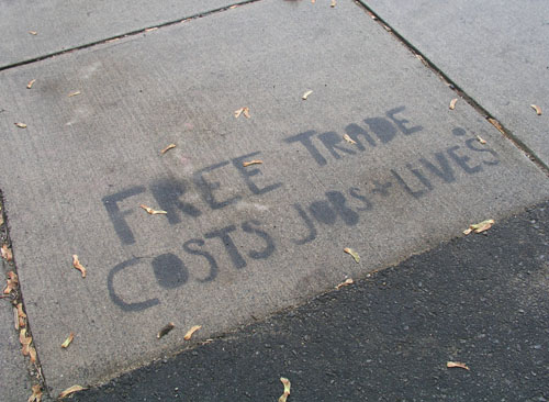 ‘FREE TRADE COSTS JOBS + LIVES’ painted on a sidewalk.