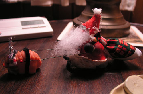 Santa ornament: freakish bready eyes, seashell sleigh, dinosaur-based reindeer, supersized beard.