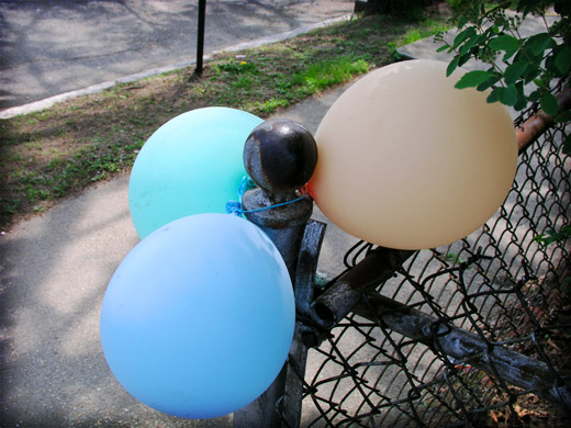 Colored balloons around a chain fence.